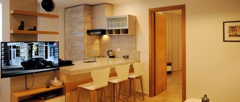 Una cocina moderna con barra, televisor de pantalla plana y mesa de comedor con sillas.