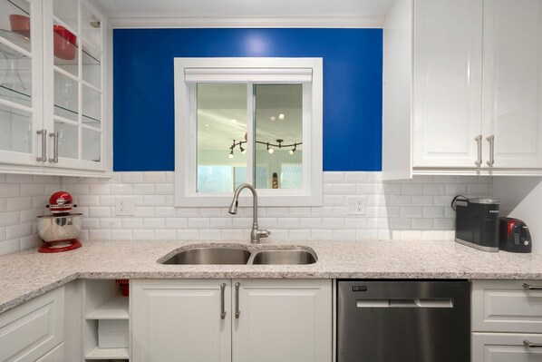 A modern kitchen with white cabinets, a double sink, and a window with a view of the interior. - Desert Oasis Retreat Pool Spa Casita (Scottsdale)