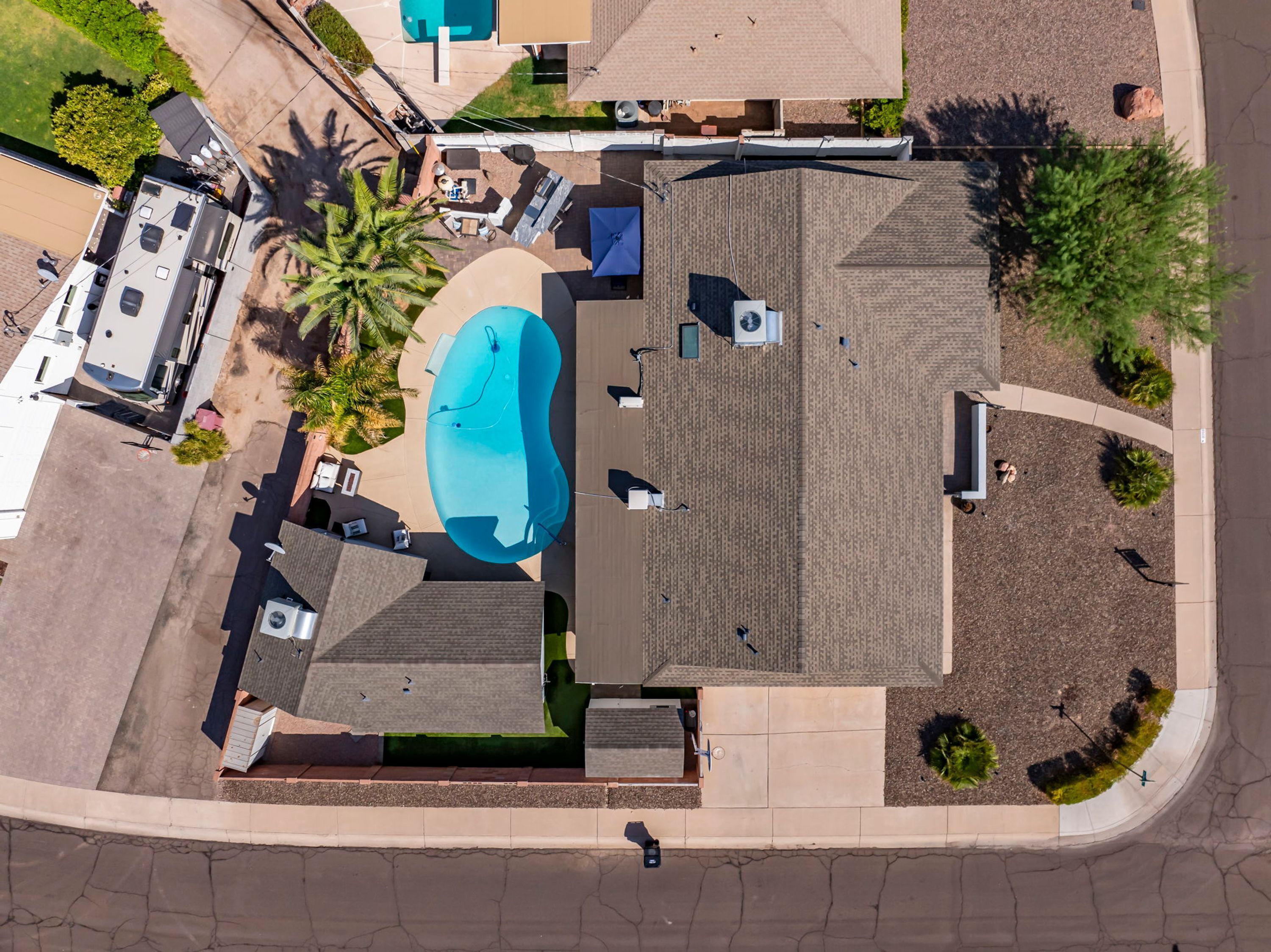 Vista aérea de una propiedad residencial con piscina, patio cubierto y garaje independiente.