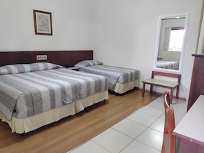 A room with two beds, a wooden floor, a small table, and a mirror. - Hotel Fazenda Fonte Colina Verde (São Pedro)