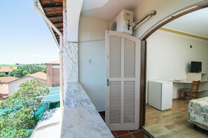A balcony with a white door, a small desk with a chair, and a television. - Hotel Fazenda Fonte Colina Verde (São Pedro)