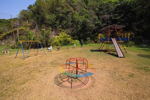 A playground with swings, a climbing structure, and a slide. - Hotel Fazenda Fonte Colina Verde (São Pedro)