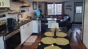 Una cocina funcional con estufa, lavamanos y zona de comedor con mesa y sillas.