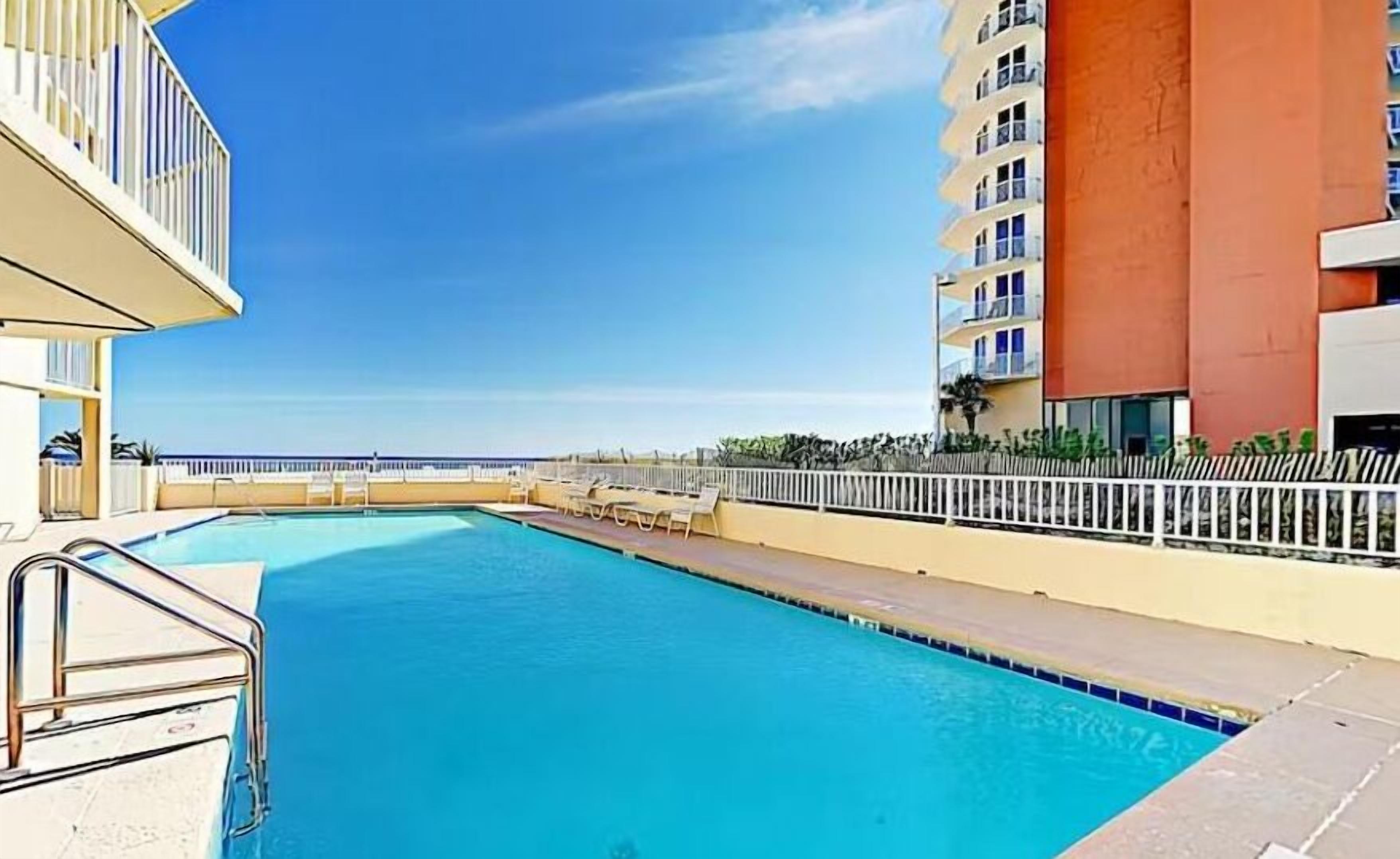 A swimming pool with a view of the ocean, surrounded by buildings.