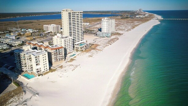 A coastal area with beachfront hotels, a sandy beach, and a clear blue ocean. - Beach Front 3BR Condo | Gorgeous Views | Whaler 2D (Gulf Shores)