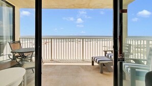 A balcony with a view of the beach, a table, chairs, and a bench. - Beach Front 3BR Condo | Gorgeous Views | Whaler 2D (Gulf Shores)