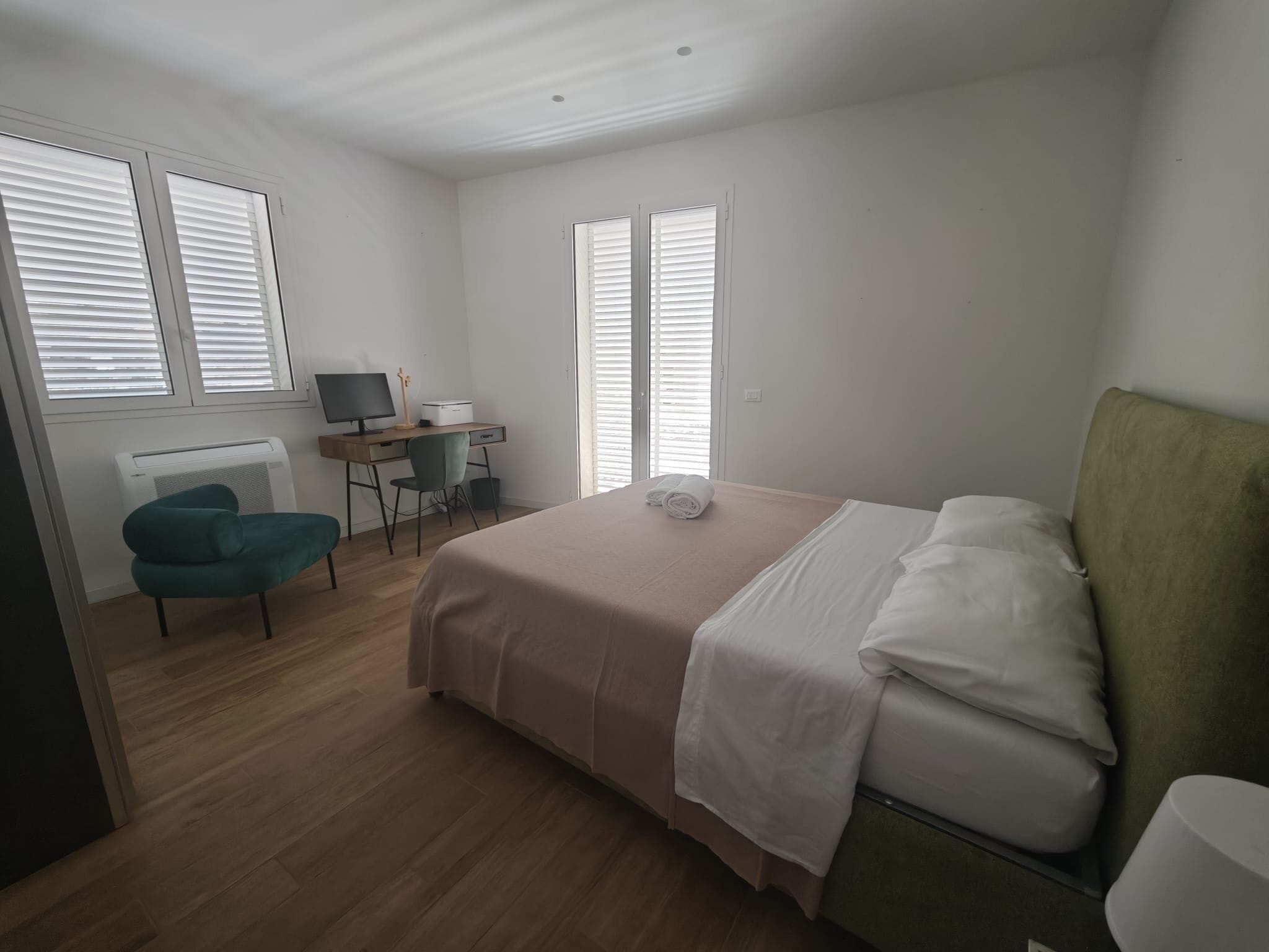 Una camera da letto con un letto, una scrivania, una sedia e un termosifone.