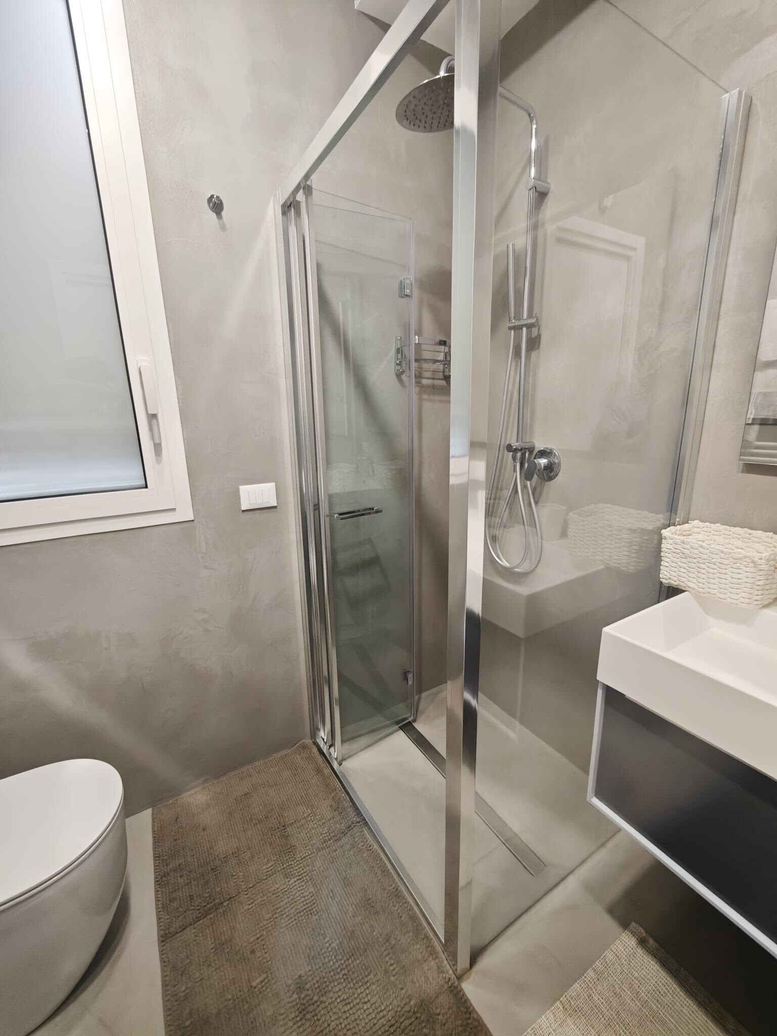 Une salle de bain moderne avec une douche à parois de verre, un lavabo blanc et des toilettes.