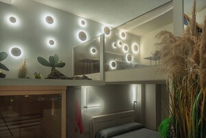Ein modernes Hotelzimmer mit einem Etagenbett, einem kleinen Schreibtisch und einem Spiegel.