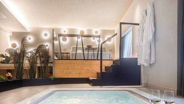 A modern spa area with a hot tub, wooden seating, and a staircase leading to a balcony. - zen escape (San Gregorio di Catania)
