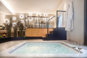 Ein moderner Wellnessbereich mit Whirlpool, Holzmöbeln und einer Treppe, die zu einem Balkon führt.