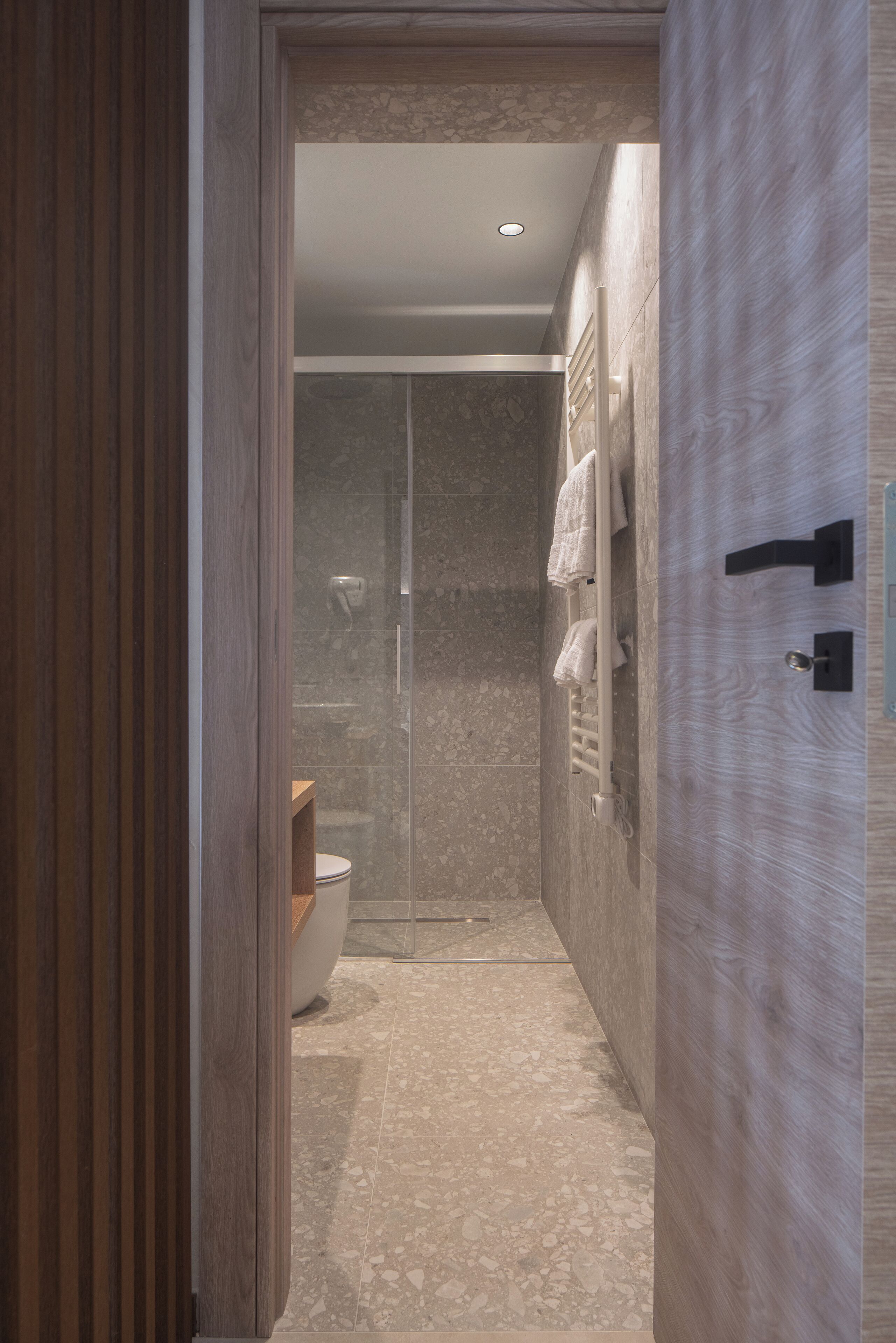 A modern bathroom with a shower, a toilet, and a towel rack.