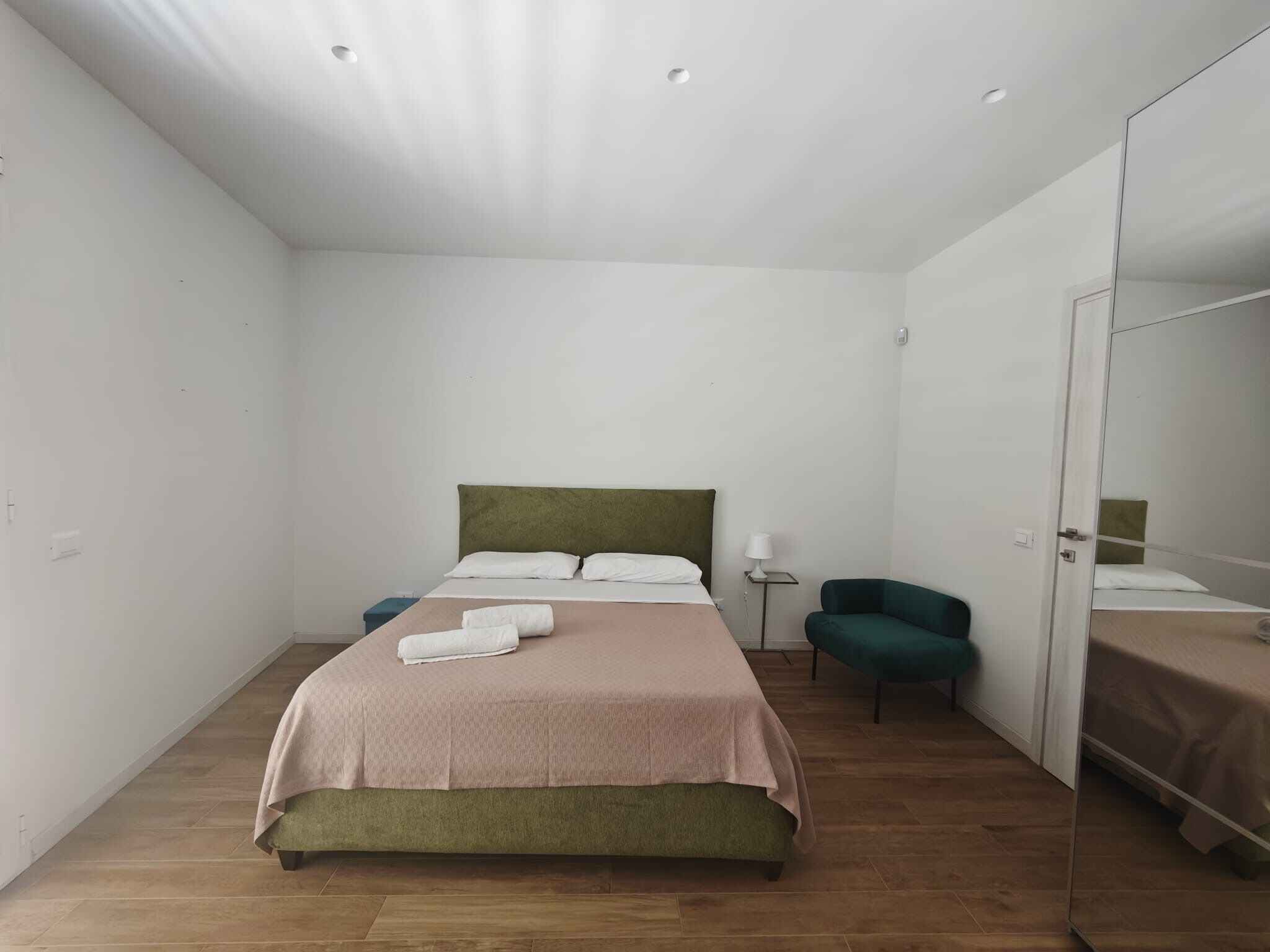 Un dormitorio con cama, una silla, una mesita de noche y un armario.