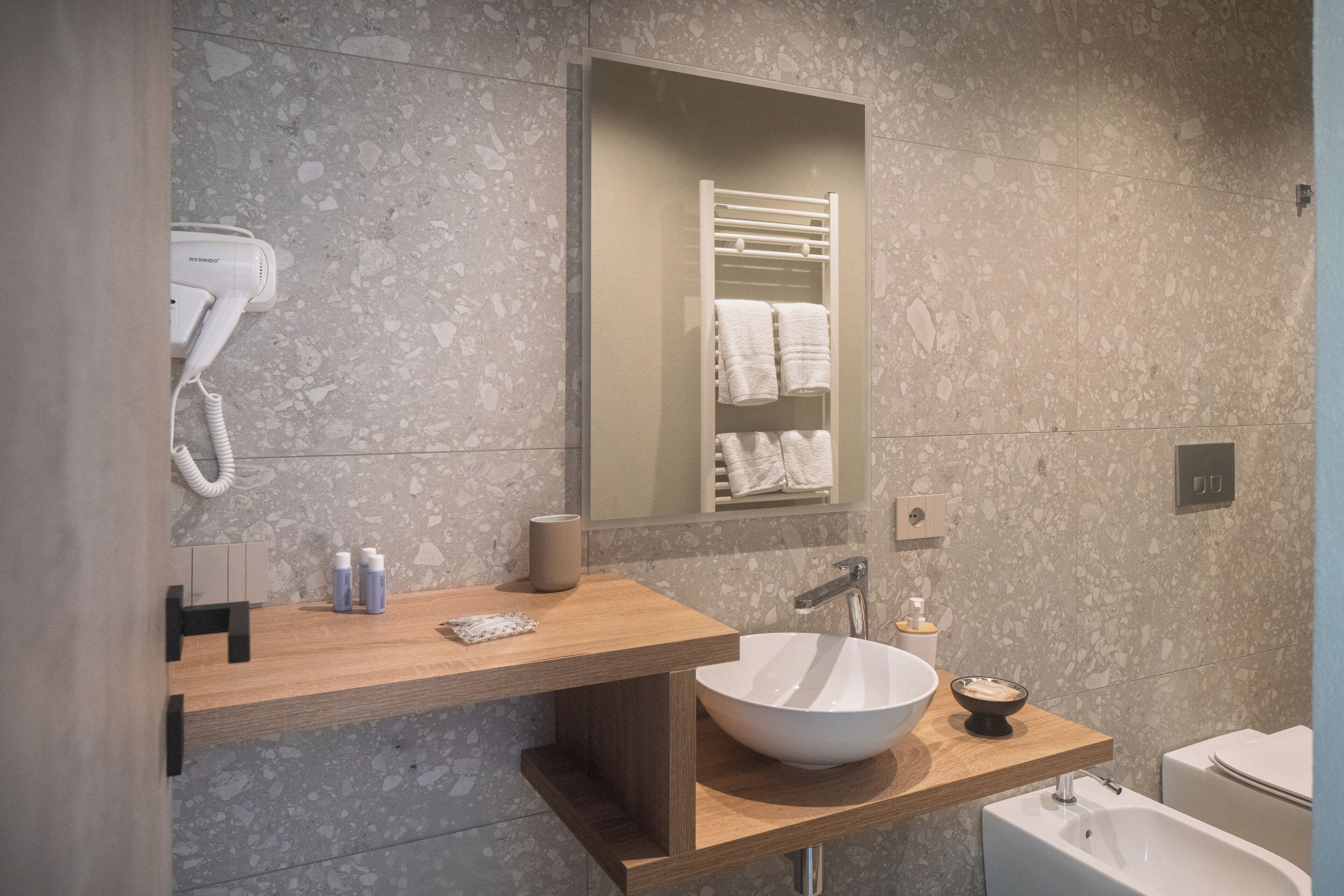 Un bagno moderno con un lavandino ampio, un asciugacapelli e uno specchio.