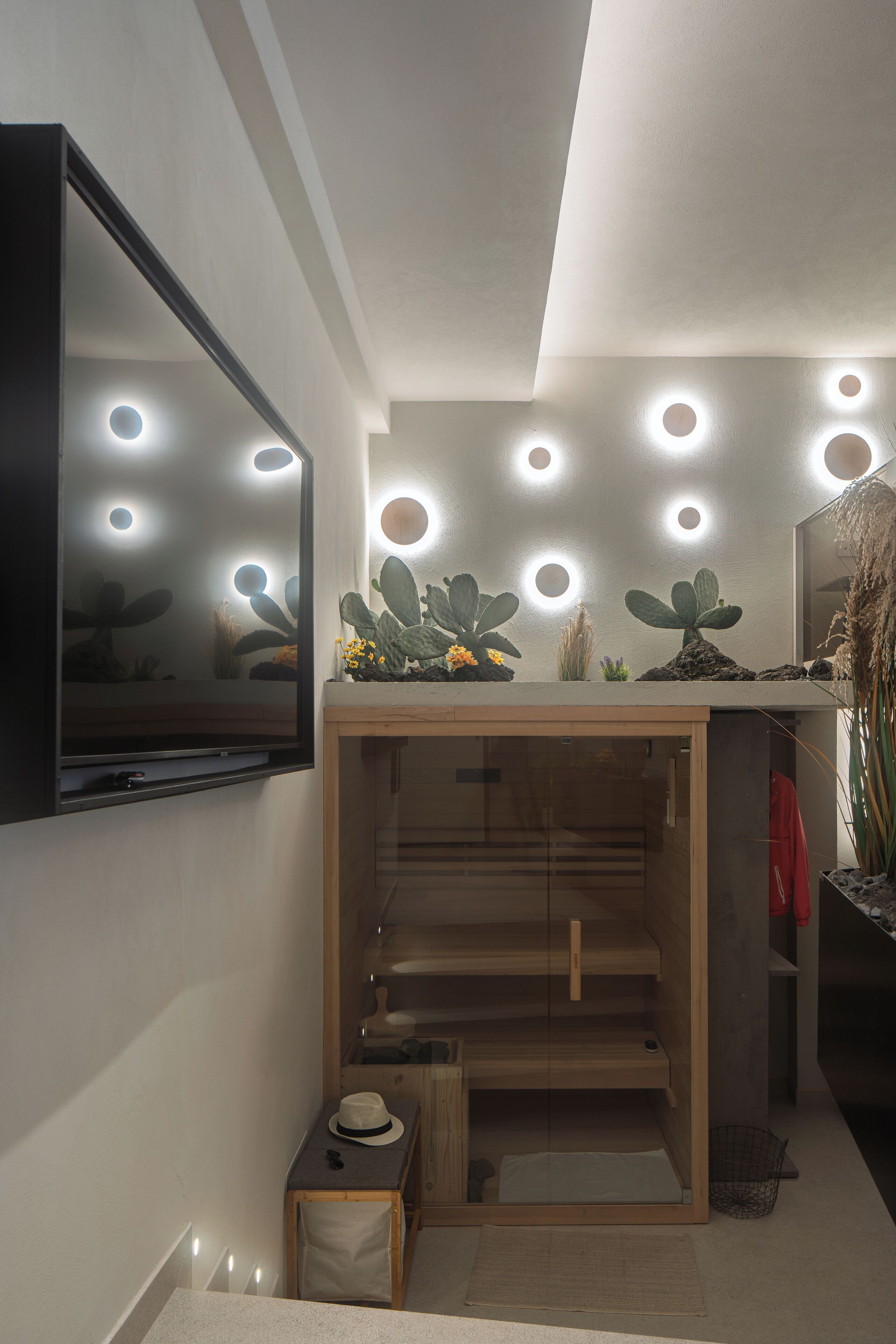 A modern bathroom with a mirror, recessed ceiling lights, a wooden vanity, and a cactus display.