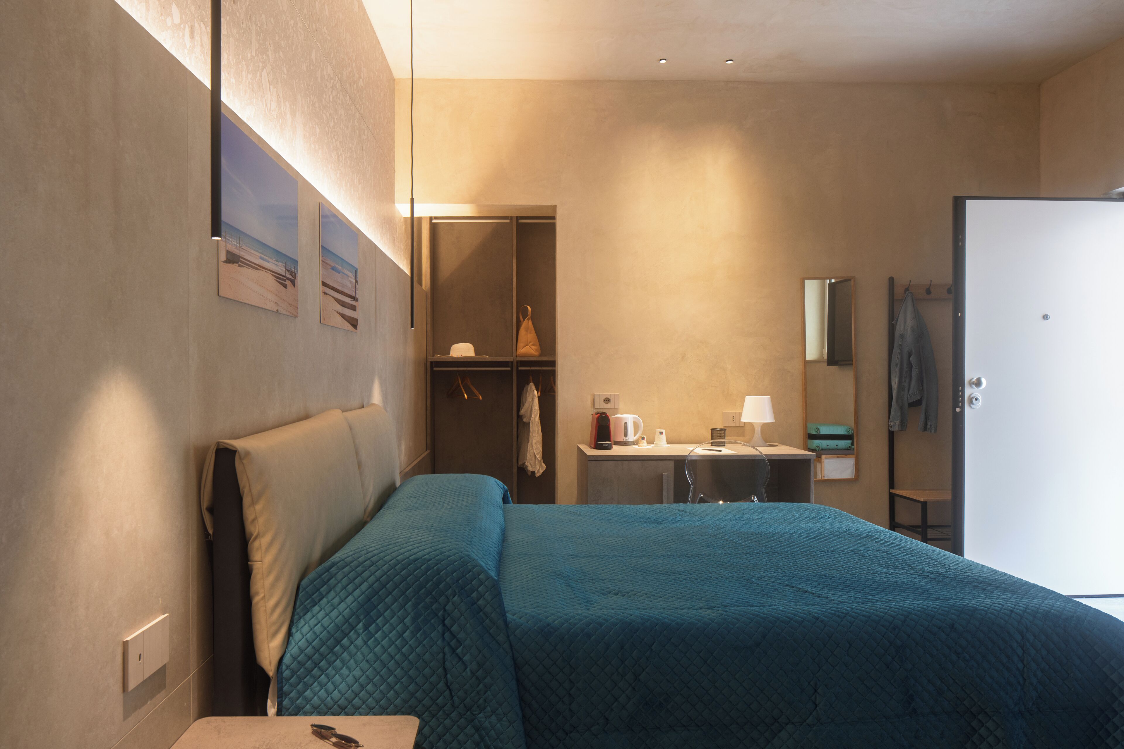 Une chambre d’hôtel avec un lit, un bureau, un miroir et une armoire.