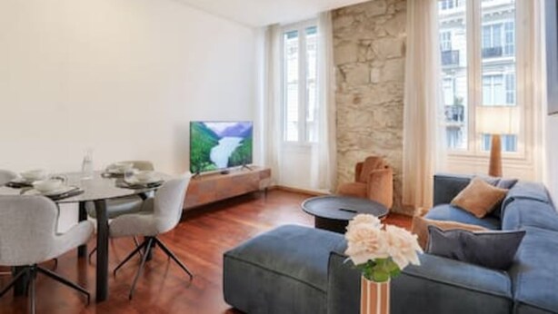 Un salon moderne comprenant un coin repas, un mur décoratif en pierre et une grande fenêtre offrant une vue sur la ville.