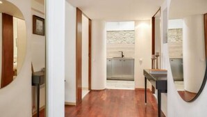 Un couloir mène à une cuisine dotée d’un pare-feu en pierre et de meubles de rangement modernes.