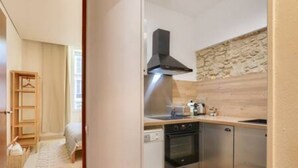 Une cuisine compacte équipée d’un lave-vaisselle, d’un four et d’un pare-feu en pierre.