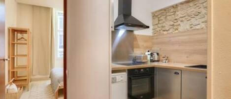A compact kitchen with a dishwasher, oven, and a stone backsplash.