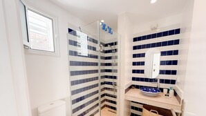 A bathroom with a glass-enclosed shower, a toilet, a sink with a mirror, and a tiled backsplash. - The Amazing Studio in Site Arch Ologique de Carthage (La Marsa)