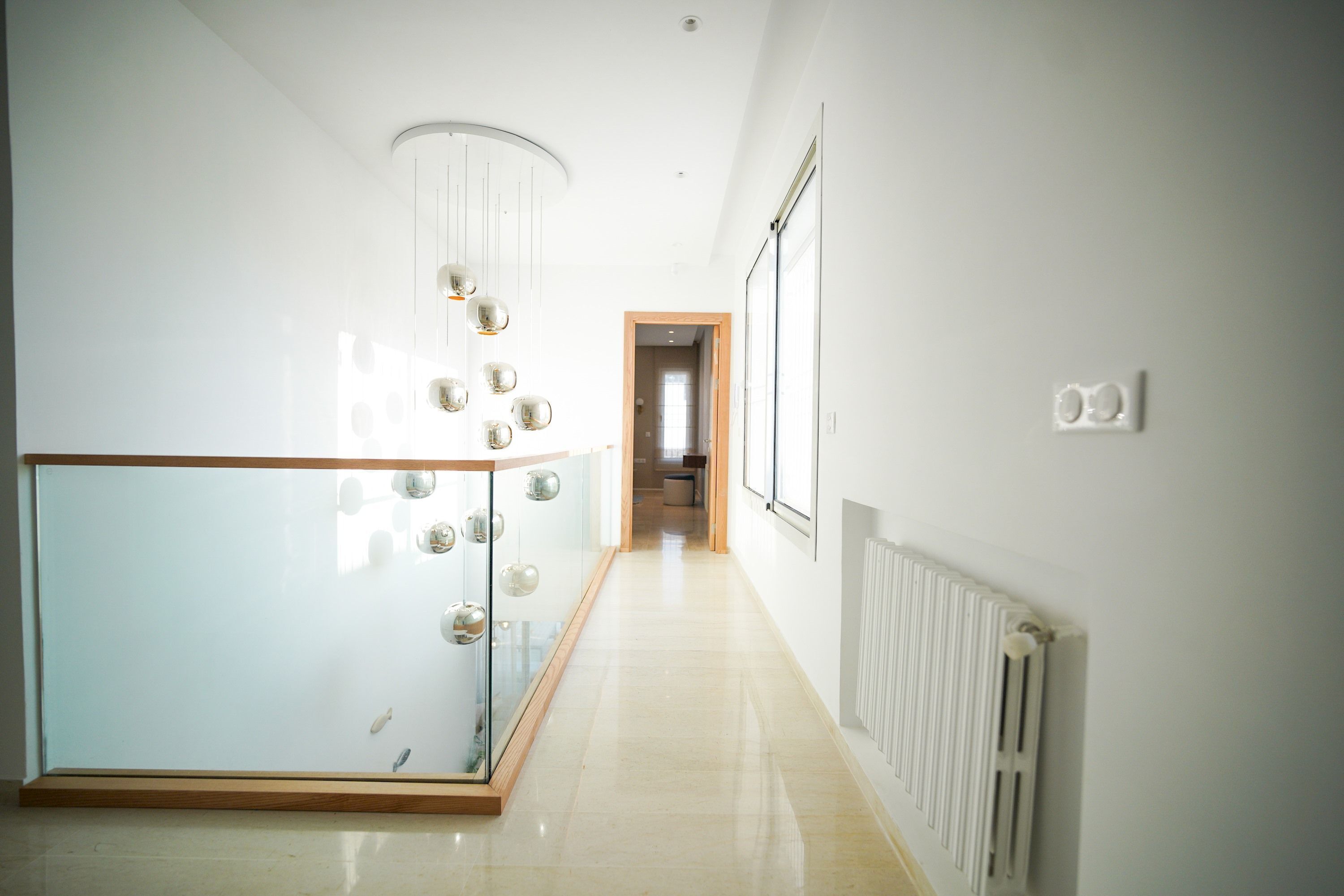 A modern hallway with a glass partition, a ceiling light fixture, and a radiator.