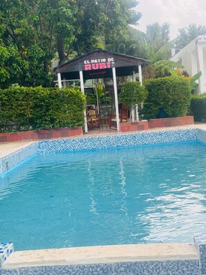 A swimming pool with a tiled edge and a gazebo labeled "El Patio de Rubi".