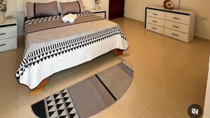 A bedroom with a bed, a nightstand, a dresser, a television, and a ceiling light. - Airisha Villa Paradise (Los Patos)