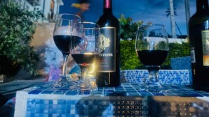 A bottle of wine, two glasses, and a tiled table outdoors at night. - Airisha Villa Paradise (Los Patos)
