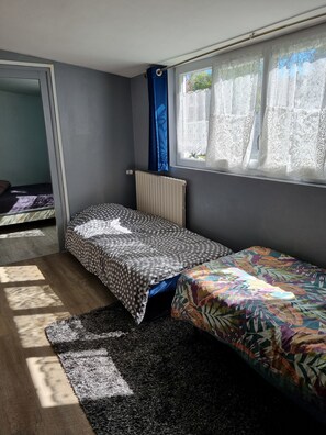 A small, compact room with two single beds, a radiator, and a window with lace curtains. - House 100 m from the sea. (Luc-sur-Mer)