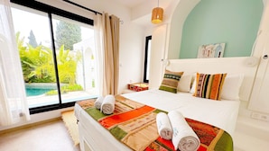 A hotel room with a bed, a view of greenery, a hanging light fixture, and a painting on the wall. - Villa Azur Piscine Bord de mer a Hammamet (Hammamet)