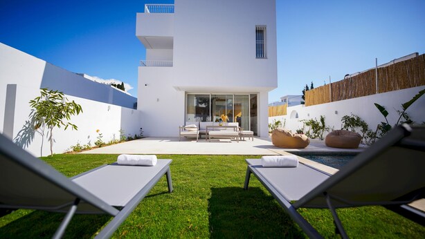 A modern house with a white exterior, a balcony, and a pool area with lounge chairs. - Villa Hermes Seaside and Luxurious (La Marsa)
