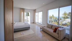 A modern bedroom with a large bed, a sofa, and a balcony with a view. - Villa Hermes Seaside and Luxurious (La Marsa)