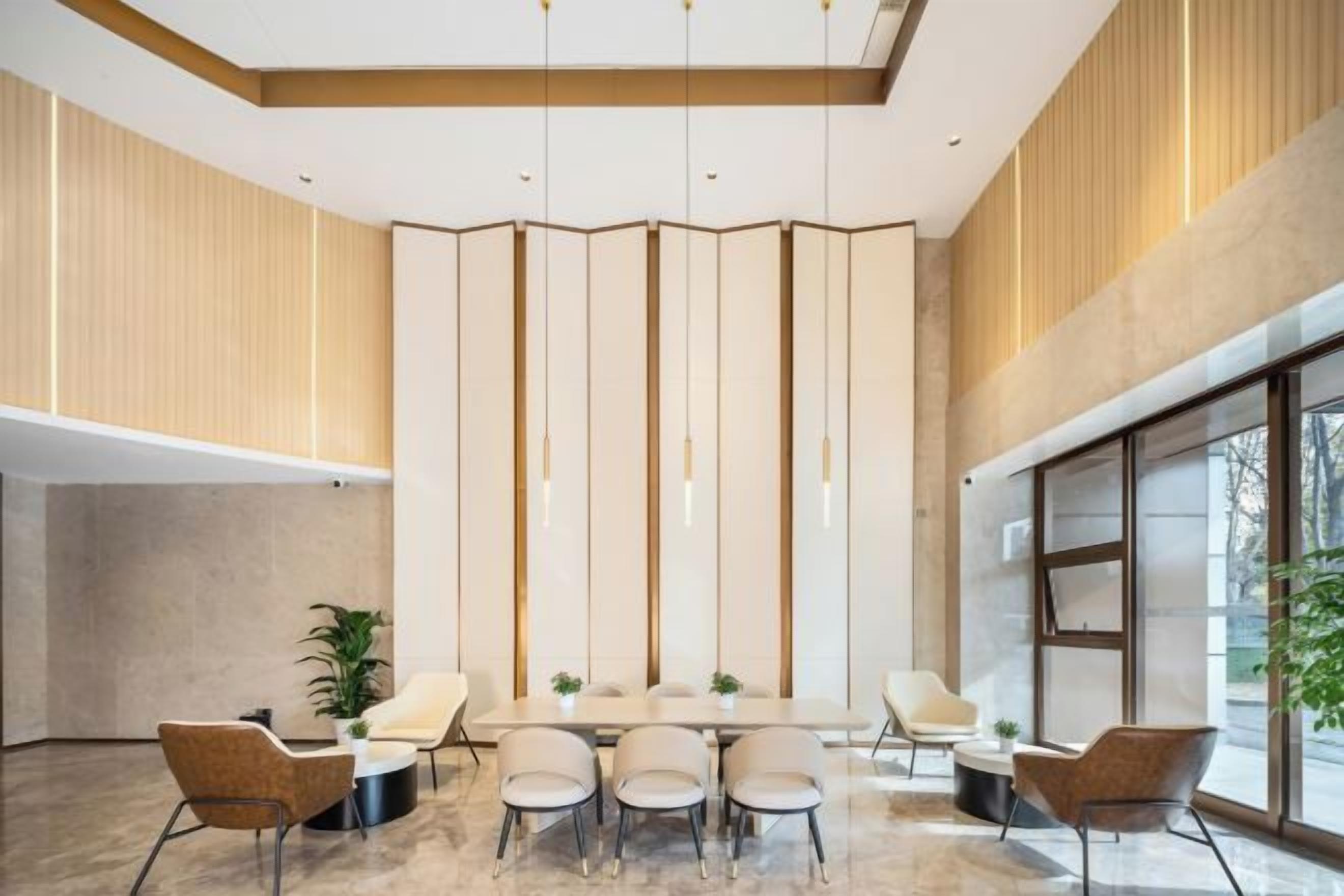 A spacious conference room with a long table and modern chairs, large windows, and a high ceiling with hanging lights.