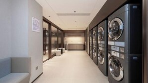 A laundry room with multiple washing machines and a bench. - Lavande Hotel (Wuhan High-speed Railway Station) (Wuhan)