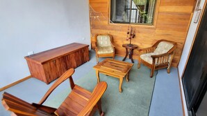 Un intérieur en bois comprenant un canapé, deux fauteuils, une petite table et un meuble en bois.