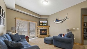 Una sala de estar con chimenea de piedra, un televisor y una escultura de un pez colgado.