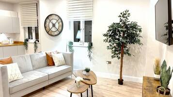 A modern living room with a sofa, coffee table, and a large potted plant.