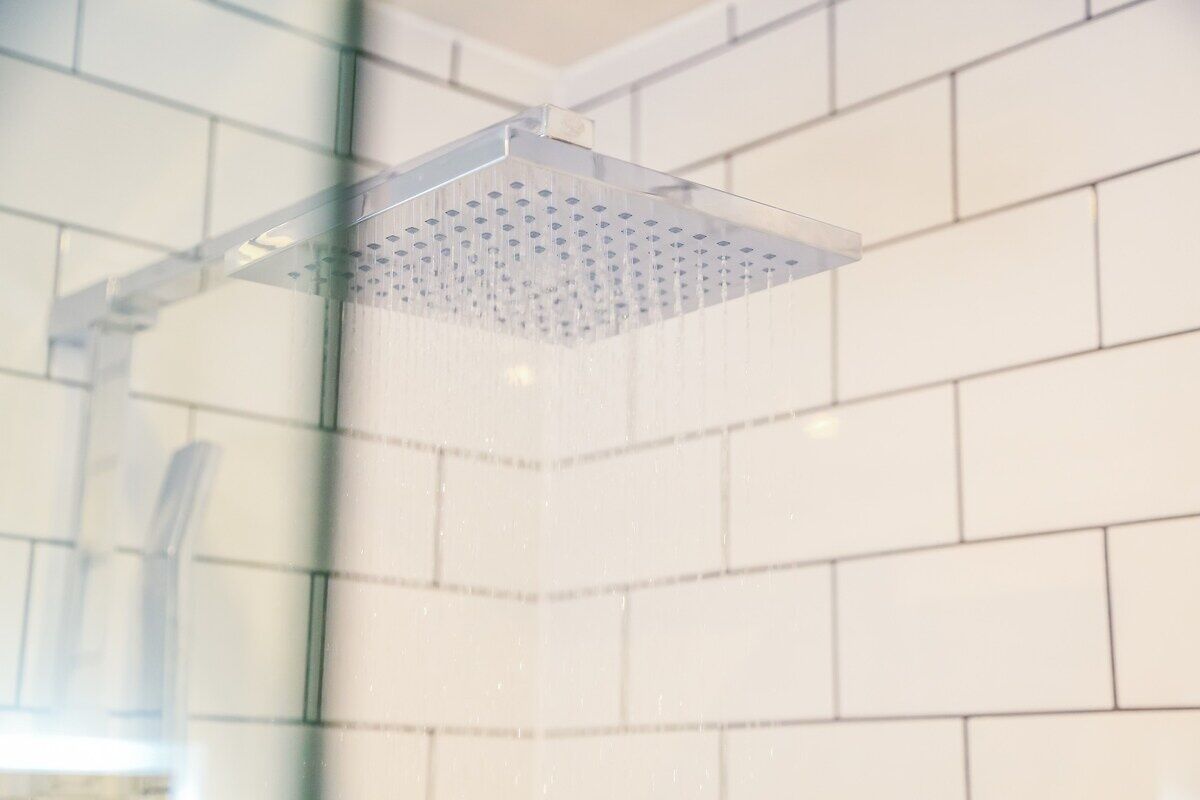 A showerhead with multiple nozzles, mounted on a wall with white tiles.