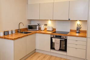 Una cocina moderna con encimera de madera, horno integrado, microondas y pileta.