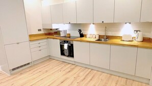 A modern kitchen with white cabinets, a wooden countertop, a built-in oven, and a sink.