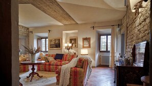 Een ruime woonkamer met een hoge plafond, een open haard en een stenen muur.