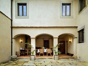 Ein Innenhof mit Essbereich, Blumentöpfen und einem Steinboden.