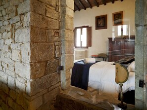 Ein Schlafzimmer mit Stehwänden, einem Bett, einem Holzkopfende, einem Nachttisch und einem Spiegel.
