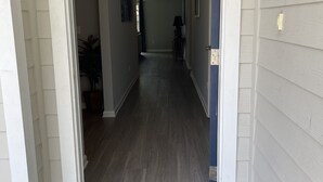 Un couloir avec un paillasson, un luminaire au plafond et une porte sur la droite.