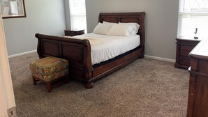 Une chambre à coucher avec un lit en bois, une table de chevet, une chaise et une commode.