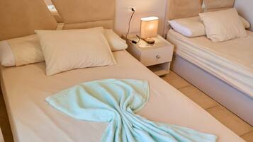 A hotel room with two beds, a nightstand with a lamp, and a towel on the bed.