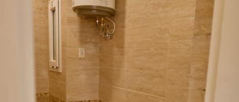A bathroom with a toilet, sink, and a water heater mounted on the wall.
