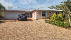 A single-story house with a garage, a driveway, and a car parked in front. - Spacious 4-bedroom house with WiFi, AC in charming Sanibel (Sanibel)