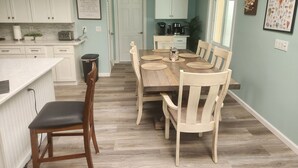 A kitchen with white cabinets, a dining table with six chairs, and a coffee machine. - Spacious 4-bedroom house with WiFi, AC in charming Sanibel (Sanibel)